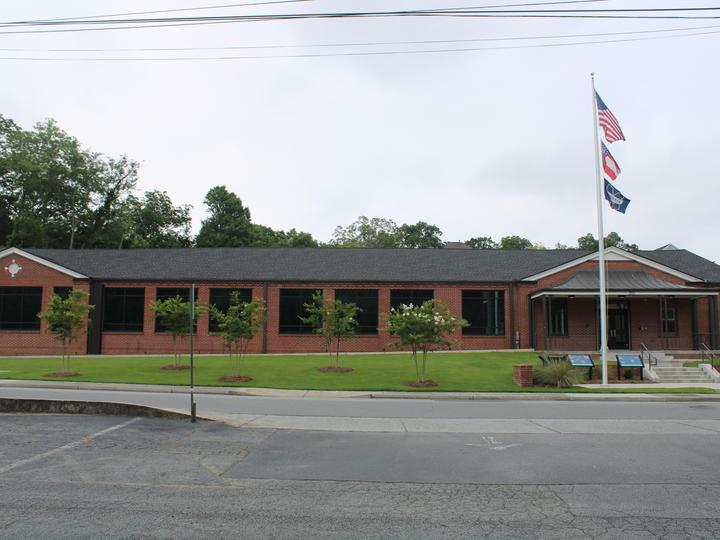 Small brown brick one-story school building with flags flying in front