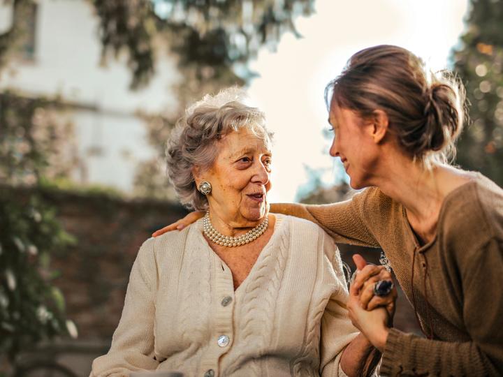 younger woman talking to an older woman and holding her hand