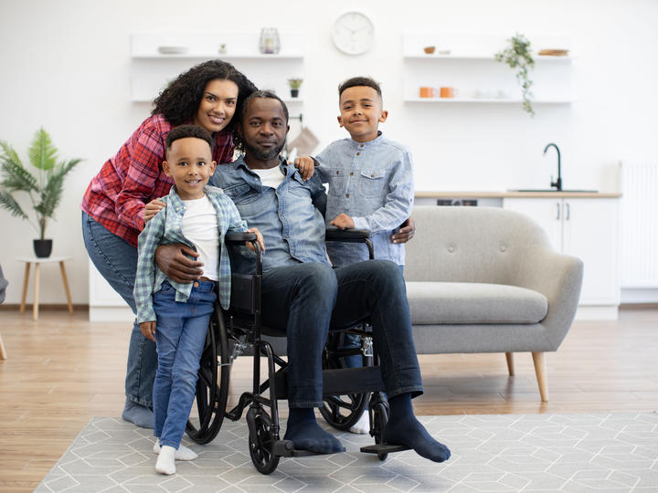 Disabled man and family members posing for a picture at home.