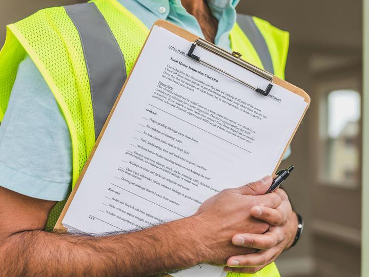 Man holding clipboard with a home inspection checklist attached.