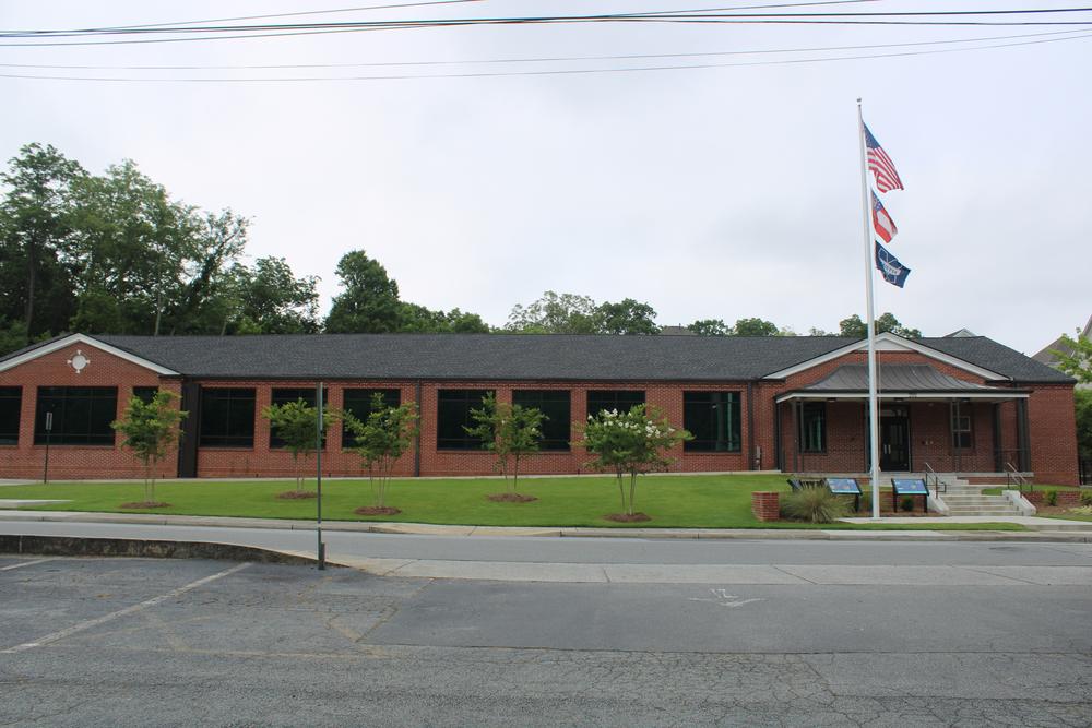 Small brown brick one-story school building with flags flying in front