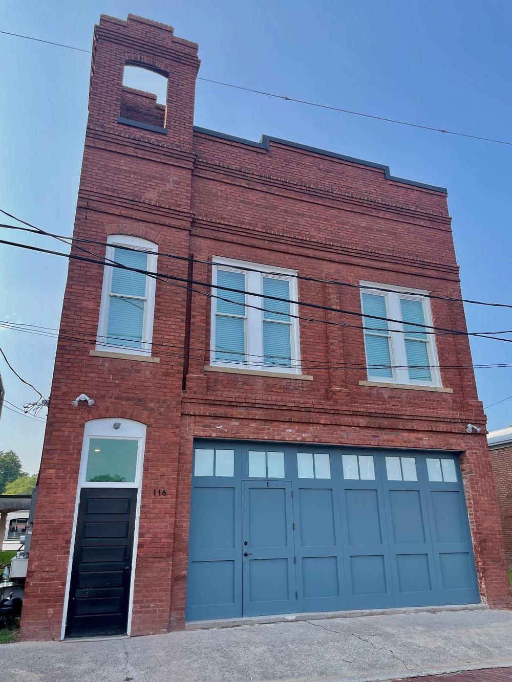 Thomson Fire Hall 3-story brown brick building with large blue garage doors